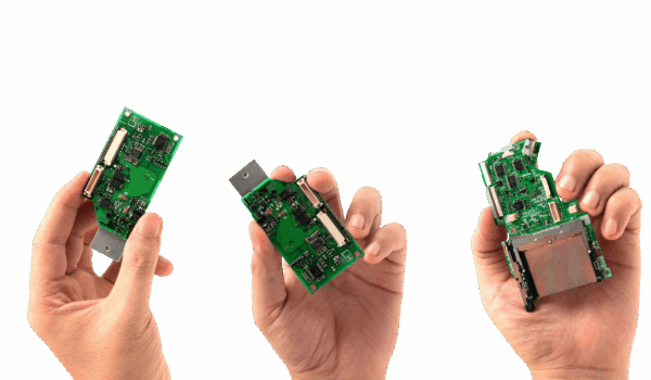 Hands holding electronic prototypes during product development.